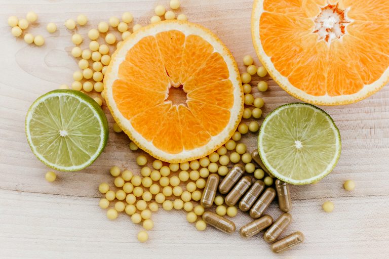 Photograph of sliced oranges and lime on a tabletop next to multiple prescription medications and supplements.